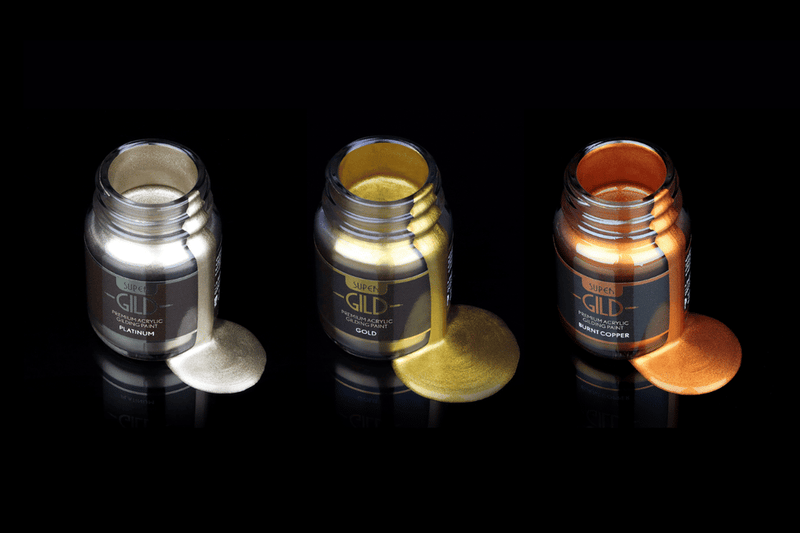 Three bottles of metallic paint labeled 'Gild' in silver, gold, and bronze on a black background.