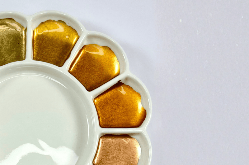 Gold-colored ice cubes in a white tray on a light gray background