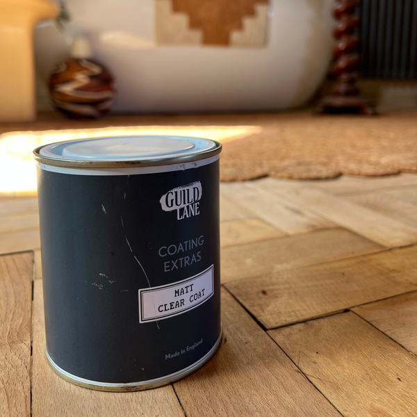 Can of Guild Lane coating on a wooden floor