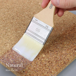 
                      
                        Paint brush with white paint on a cork surface, labeled 'Natural Matt Finish'.
                      
                    