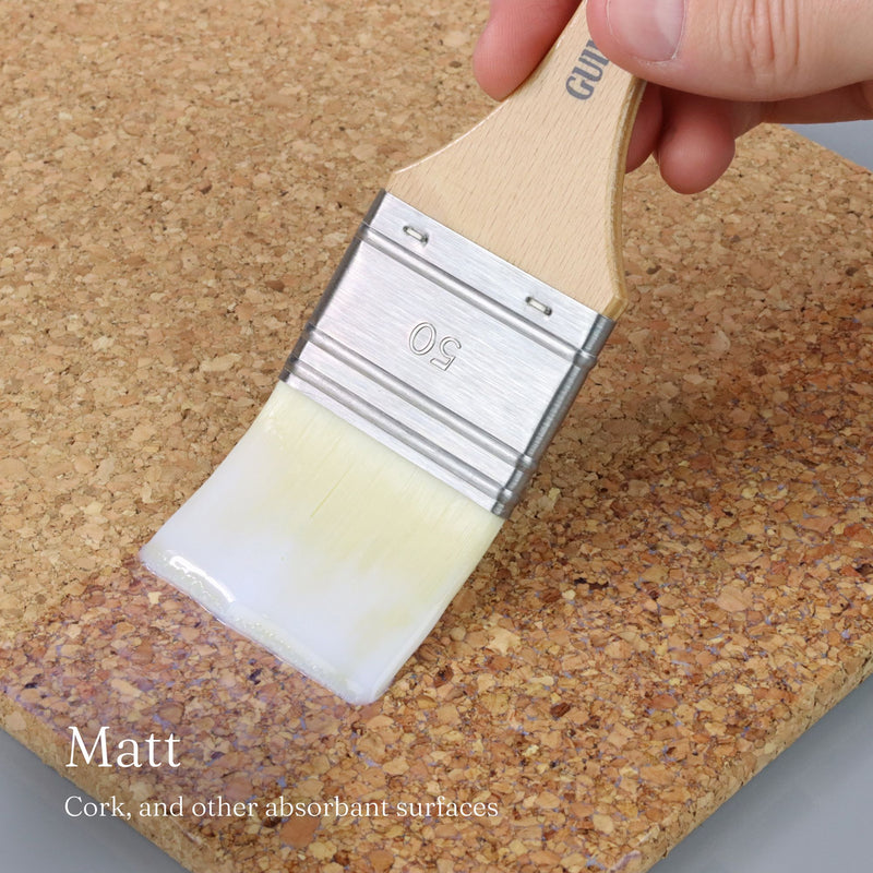 Paint brush with white paint on a cork surface, labeled 'Natural Matt Finish'.
