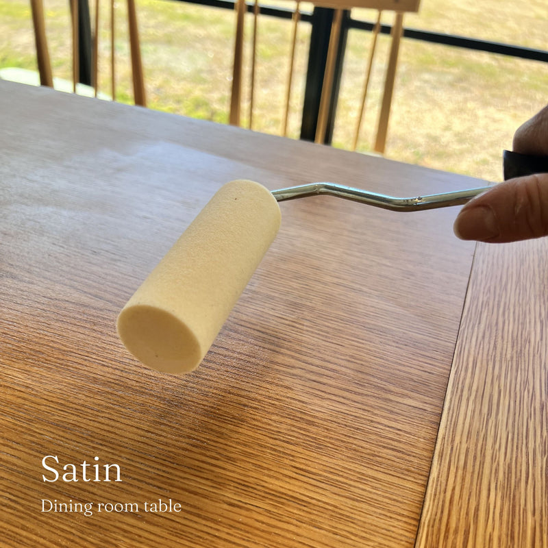 Person using a roller to apply satin finish to wooden furniture.