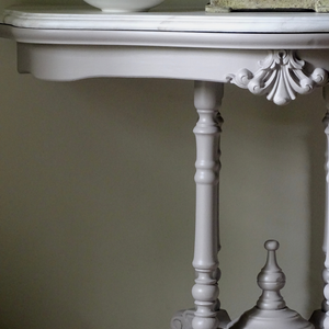 
                      
                        Transvaal grey ornate table with decorative legs against a plain wall
                      
                    