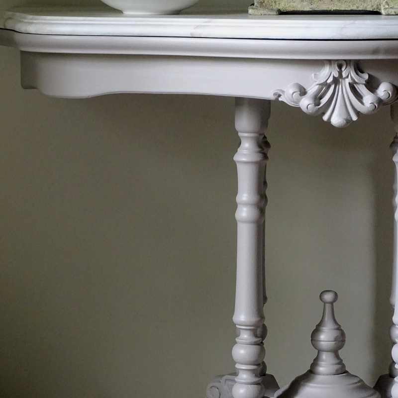 Transvaal grey ornate table with decorative legs against a plain wall