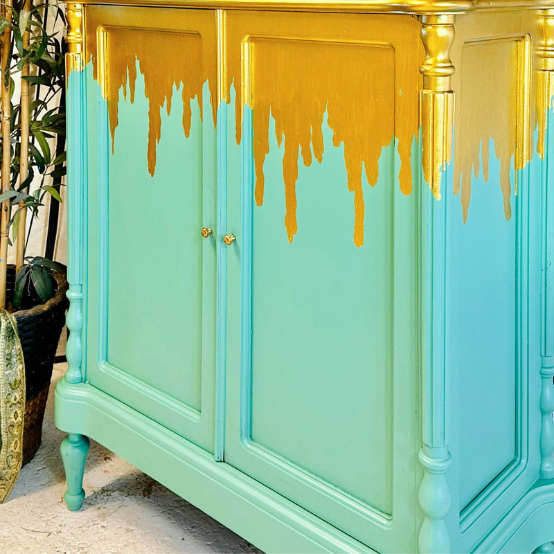 Green cabinet with gold accents and dripping paint effect