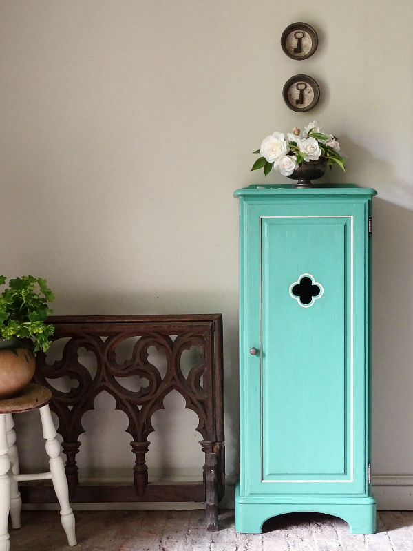 Turquoise cabinet with decorative elements in a room setting