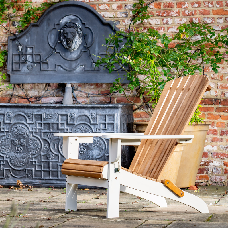 Wooden Adirondack chair on a wooden deck with decorative brick wall and metal fountain in the background.