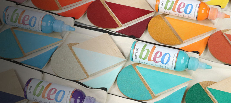 Colorful bottles of bleo paint on a geometric-patterned surface